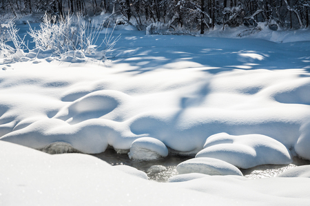Snowfall on the mountain river. Beautiful winter landscapeの写真素材