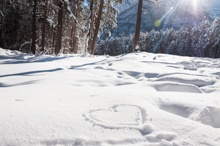 Heart on the snow. Winter landscape in the mountain at sunsetの写真素材