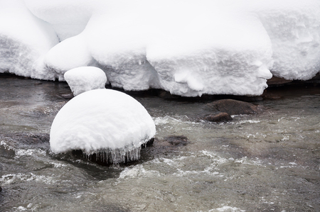 Snowfall on the mountain river. Beautiful winter landscape.の写真素材