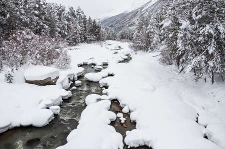 Snowfall on the mountain river. Beautiful winter landscape. Elbrus region. Caucasus, Russian Federation.の写真素材