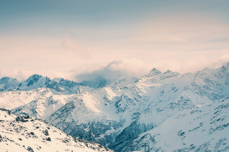 Winter snow covered mountains at sunset. Ski resort Elbrus. Beautiful winter landscape. Vintage effectの写真素材