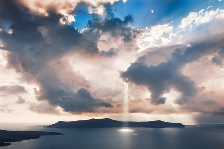 Beautiful sunset on Santorini island, Greece. Fantastic overcast sky and sunbeams through the clouds