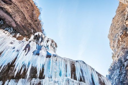 Frozen waterfall in the mountains at sunset. Beautiful winter landscape.の写真素材