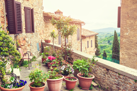 Terrace with flowers in an ancient italian house. Medieval town San Gimignano, Tuscany, Italyの写真素材