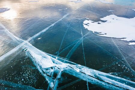 Blue ice on the frozen lake at sunset. Beautiful winter landscapeの写真素材