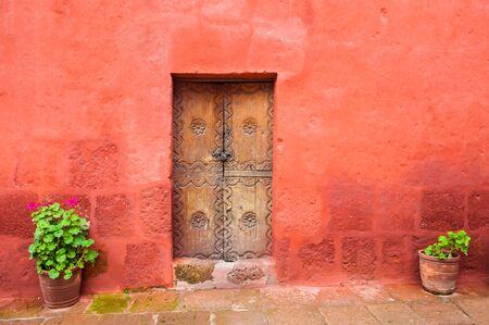 Red wall and old wooden door. Architecture in Arequipa, Peruの写真素材
