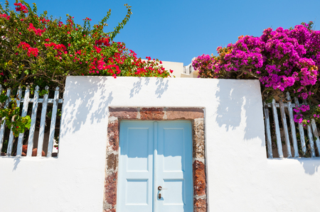 White architecture, blue door and pink flowers. Santorini island, Greece.の写真素材
