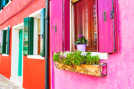 Window with pink shutters and flowers. Colorful houses on Burano island, Venice, Italyの写真素材