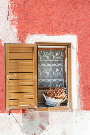 Window with decorative flowers and red wall. Colorful houses in Burano, Venice, Italyの写真素材