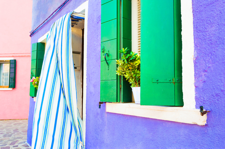 Violet wall and window with green shutters. Colorful houses in Burano island, Venice, Italyの写真素材