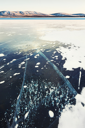 Cracked ice with bubbles on the frozen lake. Beautiful winter landscapeの写真素材