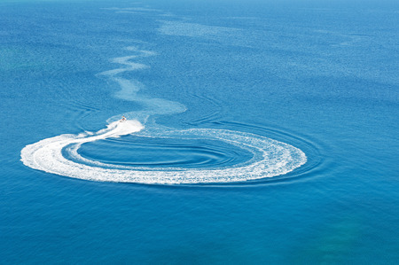 Jet ski glides on the sea and makes curve lines on the water surfaceの写真素材