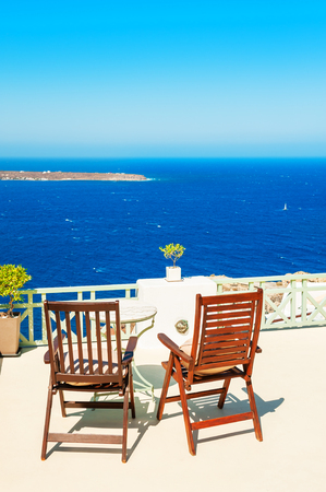 Two chairs on the terrace overlooking the sea. Santorini island, Greece. の写真素材