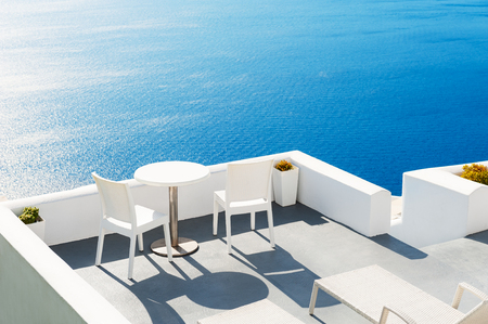 Two chairs with table on the terrace overlooking the sea. Santorini island, Greece.の写真素材