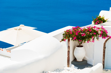 Pink flowers on the terrace with sea view. White architecture on Santorini island, Greece.の写真素材