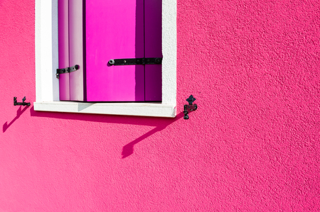 Pink wall of the house and window with pink shutters. Colorful architecture in Burano island, Venice, Italy.の写真素材