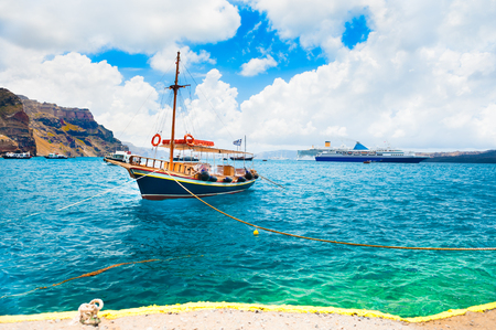 Boat in the port of Santorini island, Greece. Beautiful sea coast with turquoise waterの写真素材