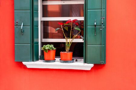Window with green shutters on the red wall. Colorful architecture in Burano island, Venice, Italy.の写真素材