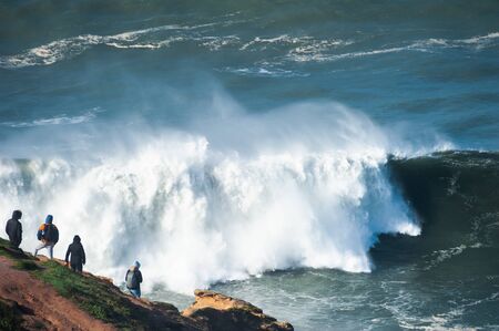People watching big waves in Nazare, Portugal. Season of big waves lasts here from November to Marchの写真素材