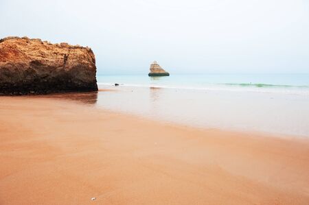 MIsty morning on the shore of Atlantic ocean in Algarve, Portugal. Beautiful summer seascapeの写真素材