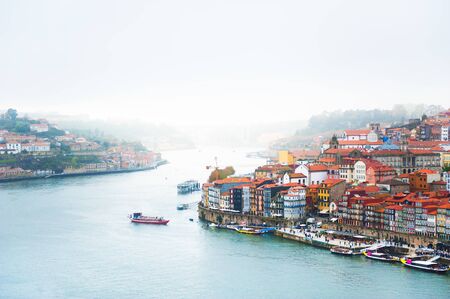 Misty morning in Porto, Portugal. Old architecture with red roofs and Douro riverの写真素材