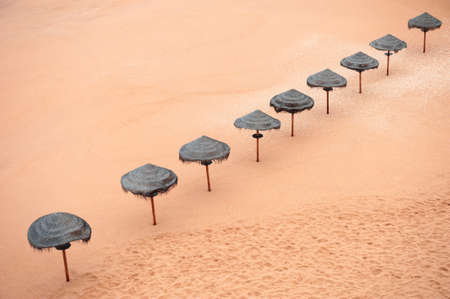 Sun umbrellas on the sandy beach. Top view. Beautiful coast of Atlantic ocean in Algarve, Portugal. Summer travel background.の写真素材