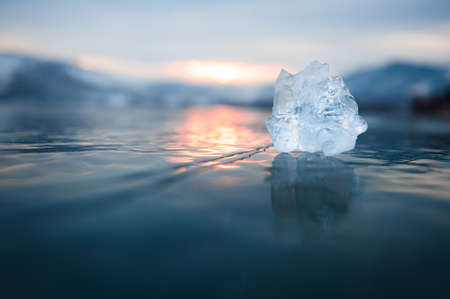 Ice on the frozen lake at sunset. Macro image, shallow depth of field. Winter nature background