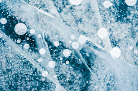 Texture of blue ice with cracks and air bubbles on the frozen lake. Macro image. Winter nature backgroundの写真素材