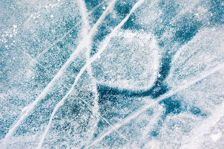 Texture of blue ice with cracks and air bubbles on the frozen lake. Macro image. Winter nature backgroundの写真素材