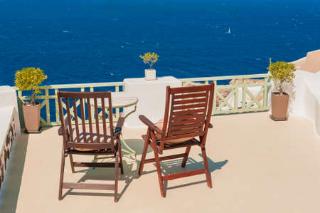 Santorini island, Greece. Two chairs on the terrace with sea view. Famous travel destination