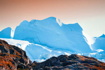 Big blue icebergs in Ilulissat icefjord at sunset, western Greenland. Summer landscape