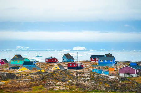 Colorful houses in Saqqaq village and view of the icebergs in Atlantic ocean, western Greenland. Summer landscapeの写真素材