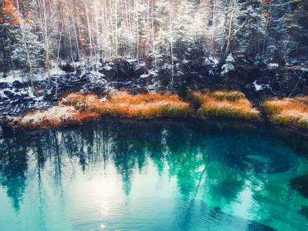 Blue geyser lake in autumn forest after snowfall. Altai mountains, Siberia, Russia. Turquoise lake and snow-covered treesの写真素材