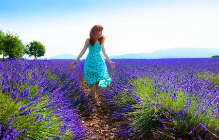 Young beautiful woman in blue dress walking on lavender field in Provence, France. beautiful summer landscape. summer travel conceptの写真素材