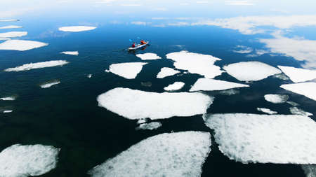 Kayak sailing between ice floes on the lake. Aerial drone view. Baikal lake, Siberia, Russia. spring landscapeの写真素材