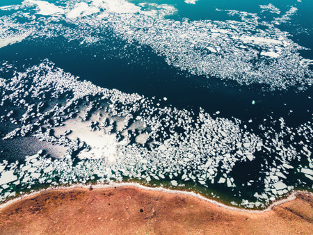 Melting ice floes on the coast of lake. Baikal lake, Siberia, Russia. aerial view. beautiful spring landscape. Clear blue water with ice floatsの写真素材