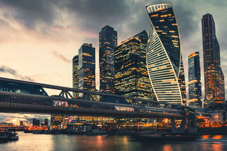 Modern glass skyscrapers with night city lights. Moscow, Russia. Night sky with clouds and glass facades of skyscrapers with lighting.の写真素材