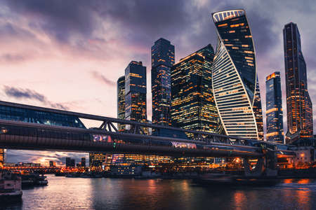 Modern glass skyscrapers with night city lights. Moscow, Russia. Night sky with clouds and glass facades of skyscrapers with lighting.の写真素材