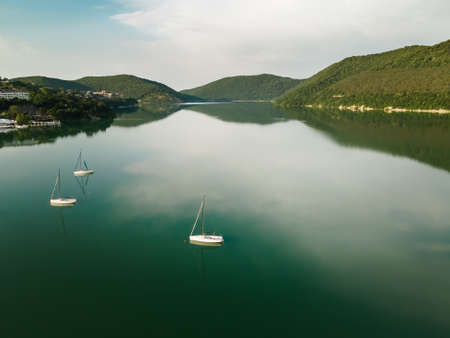 Mountain lake with turquoise water and yachts. Abrau lake in Abrau-Durso village, Russia. Mountains are reflected in the calm water. Summer nature landscapeの写真素材