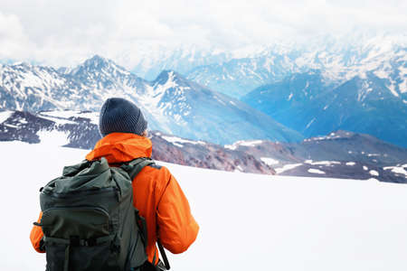 Man traveler with backpack hiking in winter mountains. Travel and outdoor activity concept