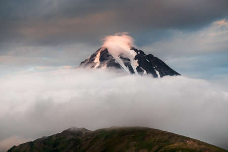 Peak of Vilyuchinsky volcano with clouds at sunset in Kamchatka, Russia. Beautiful summer landscapeの写真素材