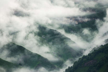 Morning fog in the mountains at sunrise. Clouds over the green mountains and hills. Beautiful summer...