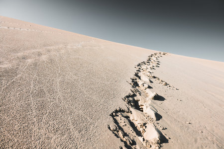 Footprints on the sand. Sandy dunes against the sky at sunset. Summer landscape. Abstract nature backgroundの写真素材