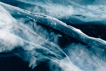 Transparent blue ice with cracks on Baikal lake in winter. Abstract winter nature background.