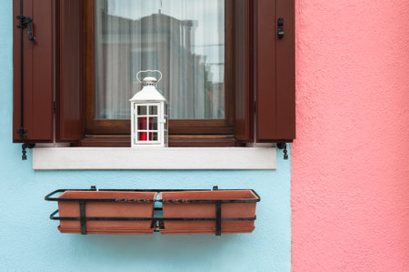 Pink and blue painted facade of the house and window with wooden shutters. Colorful architecture in Burano island, Venice, Italy.の写真素材