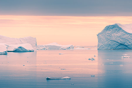 Icebergs at sunset in Greenland. Pink sky reflected in calm water surface. Atlantic ocean, Ilulissat icefjord, Greenland.の写真素材