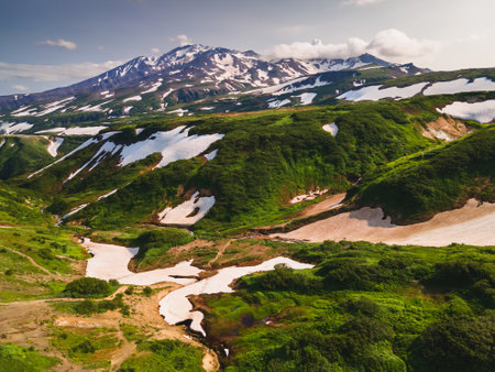 View of volcanoes with snow and hills with green grass in Kamchatka, Russia. Beautiful summer landscapeの写真素材
