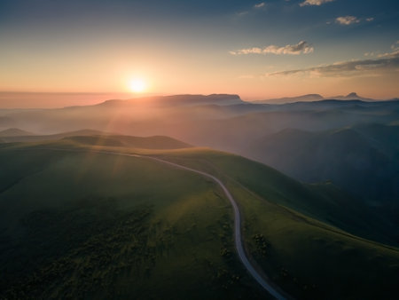 Road in the green hills at foggy sunrise. Gil-Su valley in North Caucasus, Russia. Beautiful summer landscapeの写真素材