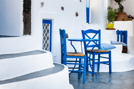 Traditional white and blue greek architecture in Santorini island, Greece. Blue chairs with table on the street.の写真素材