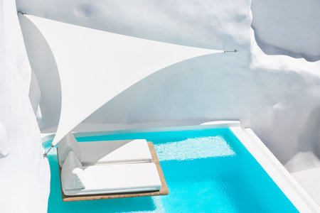 Luxury swimming pool with blue water and white chaise lounges. Santorini island, Greece. Travel and vacation conceptの写真素材